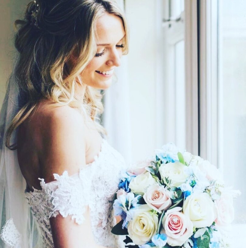 A bride in the window gazing fondly on her beautiful bridal bouquet